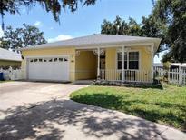 Charming yellow home featuring a welcoming front porch, two-car garage, and well-maintained front yard at 1006 Tropical E Dr, Bradenton, FL 34208