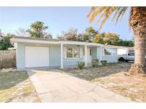 Charming single-story home with a light blue exterior, an attached garage, and a well-manicured front yard at 1131 Dartmouth Dr, Holiday, FL 34691