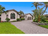 Elegant home exterior featuring a paver driveway, lush landscaping, and a well-manicured lawn at 2002 Carolina Ne Cir, St Petersburg, FL 33703