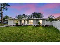 Charming single-story home with a lush green lawn and well-manicured landscaping at dusk at 2452 Bayshore Blvd, Dunedin, FL 34698
