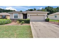 Inviting single-story home featuring a two-car garage, manicured lawn, and charming front garden at 2823 Holly Bluff Ct, Plant City, FL 33566
