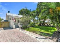 Charming home featuring lush landscaping, a brick driveway, and a quaint front porch with an American flag at 3220 W San Pedro St, Tampa, FL 33629