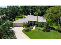 Inviting single-story home featuring a lush lawn, mature palm trees, and a convenient circular driveway at 3353 Wedgewood Way, Tarpon Springs, FL 34688