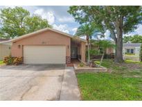 Charming single-story home with a beige exterior, a two-car garage, and beautiful landscaping at 516 7Th Se St, Largo, FL 33771