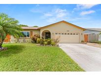 Charming home featuring a well-manicured lawn, lush landscaping, and an attached two-car garage at 6289 107Th N Ave, Pinellas Park, FL 33782