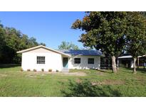 Charming single-story home featuring a metal roof, white brick facade, and a neatly manicured front lawn at 8807 Mary Ivy Dr, Plant City, FL 33567
