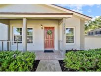 Inviting front entryway with a decorated door, lush landscaping, and charming details at 11799 Raintree Dr, Temple Terrace, FL 33617