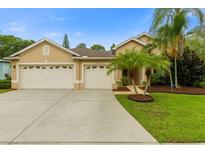 Charming home featuring a three-car garage, palm trees, and landscaped front yard at 12031 Mountbatten Dr, Tampa, FL 33626