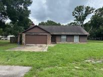 Charming single-story home with a well-maintained lawn, garage, and stone accents on the facade at 17004 State Road 54, Lutz, FL 33558