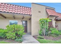 Charming front entrance with a red tile roof and a welcoming, well-maintained landscaped garden at 1701 Pinehurst Rd # 33E, Dunedin, FL 34698