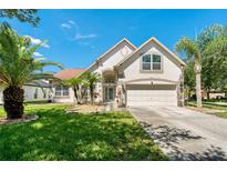 Charming two-story home featuring a lush, green lawn and beautiful palm trees at 19206 Ivy Oak Way, Tampa, FL 33647
