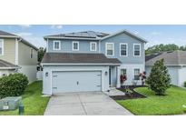 Beautiful two-story home featuring a two-car garage, solar panels, and a well-manicured lawn at 2073 Branding Iron Way, New Port Richey, FL 34655