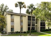 Condo exterior showcasing the multiple levels, palm trees, and landscaping at 3232 Lake Pine E Way # A2, Tarpon Springs, FL 34688