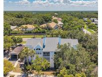 Beautiful condo featuring white exterior and gray roof, nestled among trees in lush landscaping at 3301 Haviland Ct # 301, Palm Harbor, FL 34684