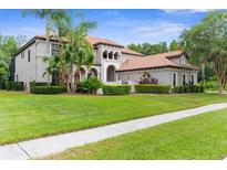 Elegant two-story home featuring a tile roof, manicured lawn, and lush tropical landscaping at 3500 Ballastone Dr, Land O Lakes, FL 34638