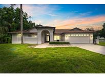 Charming single-story home featuring a well-manicured lawn and attached two car garage at sunset at 3509 Country Creek Ln, Valrico, FL 33596