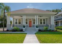 Charming home featuring a welcoming front porch, landscaped yard, and classic architectural details under a clear blue sky at 3811 N Arlington Ave, Tampa, FL 33603