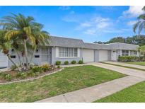 Charming townhome with a well-maintained lawn, mature palm trees, and an attached single car garage at 502 Cara Ct # 502, Largo, FL 33771
