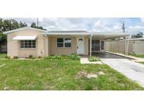 Charming single-story home featuring a covered porch and carport, complemented by a well-maintained lawn at 5221 48Th N Ave, St Petersburg, FL 33709