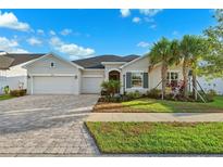 Charming home boasts a three-car garage, manicured lawn, and meticulously laid paver driveway at 6035 Nikki Ln, Odessa, FL 33556