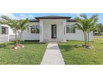 A charming home features a walkway leading to the front door, a lush lawn, and palm trees adding to the curb appeal at 711 42Nd S Ave, St Petersburg, FL 33705