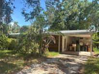 Modest single story home with brick accents, carport, and mature trees in an overgrown lot at 729 41St St, Sarasota, FL 34234