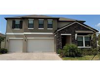 Beautiful two-story home featuring a two-car garage, stone accents, and manicured landscaping at 8922 Little Bluestem Dr, Land O Lakes, FL 34637