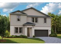 Charming two-story home features a two-car garage and a well-manicured lawn, set against a backdrop of lush trees and blue sky at 9933 Surrey Rose Dr, San Antonio, FL 33576