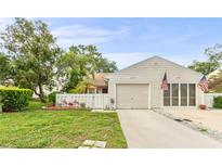 Charming single-Gathering home with manicured lawn, attached garage, and enclosed front porch at 12529 Knollbrook Ln, Hudson, FL 34669