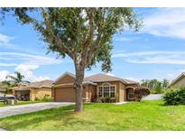 Charming single-story home with a well-maintained lawn, mature tree and a two-car garage at 12631 Chenwood Ave, Hudson, FL 34669