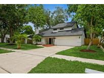 Charming two-story home featuring a well-manicured lawn, mature trees, and a welcoming front entrance at 14909 Oldgate Pl, Tampa, FL 33624