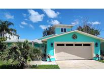 Charming turquoise home featuring a well-maintained lawn, two-car garage, and a lovely color scheme at 1626 Sea Breeze Dr, Tarpon Springs, FL 34689