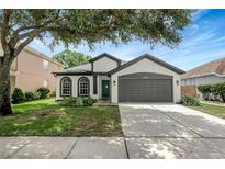 Charming single-Gathering home featuring a well-manicured lawn, a two-car garage and three arched windows at 22824 Marsh Wren Dr, Land O Lakes, FL 34639