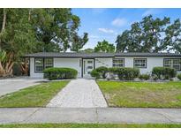 Charming single-story home featuring a well-maintained lawn, mature trees, and a welcoming walkway at 4704 W Fairview Hts, Tampa, FL 33616