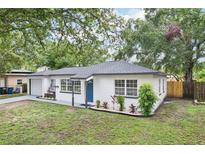 Charming single-story home with white exterior, blue front door, well-manicured lawn, and nicely landscaped front garden at 6 N Orion Ave, Clearwater, FL 33765