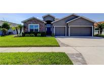 Charming single-story home featuring a well-manicured lawn, a two-car garage and stone facade accents at 6648 Castle Green Pl, Zephyrhills, FL 33541