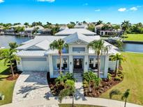 Stunning waterfront home featuring lush landscaping, a metal roof, and inviting front porch perfect for relaxing at 718 Pinckney Dr, Apollo Beach, FL 33572