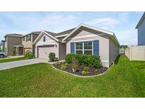 Charming single-story home featuring a manicured lawn, neutral paint, blue shutters, and a two-car garage at 7774 Sail Clover Ln, Zephyrhills, FL 33540