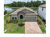 Charming single-story home featuring a brick driveway and a well-manicured front lawn with water view at 12646 Oak Hill Way, Parrish, FL 34219