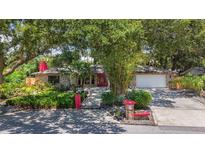 Charming single-story brick home featuring a red door, lush landscaping, and a well-manicured lawn at 2439 Madrid Ave, Safety Harbor, FL 34695