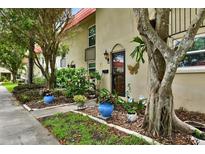 Charming exterior view of a townhouse with mature trees, landscaping and a red tile roof at 2700 Bayshore Blvd # 544, Dunedin, FL 34698