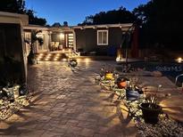 Stunning backyard with a pool, stone walkways, ambient lighting and outdoor seating areas at 3012 Grand View Ave, Clearwater, FL 33759