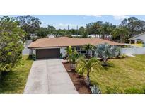 Charming single-story home featuring a well-manicured lawn, a long driveway, and a 2-car garage at 309 Palmetto Ln, Largo, FL 33770