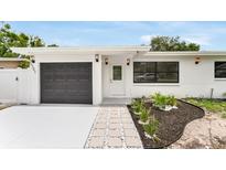 Charming single-story home with modern black garage door and stone walkway at 3381 19Th Sw Pl, Largo, FL 33774