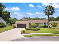Charming single-story home with a well-manicured lawn, mature landscaping, and a welcoming screened entryway at 37147 Foxrun Pl, Zephyrhills, FL 33542