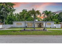 Charming single-story home featuring mature landscaping and a welcoming facade with a black front door at 521 51St S Ave, St Petersburg, FL 33705