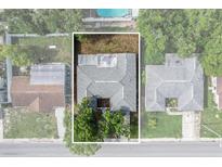 Aerial view of a house with a gray roof, green trees, and surrounding neighborhood at 7040 Fox Hollow Dr, Port Richey, FL 34668