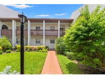 Inviting condo exterior featuring a well-maintained lawn and pathway to the entrance at 7614 Radcliffe Cir # 202B, Port Richey, FL 34668
