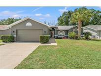 Charming single Gathering home showcasing a well-manicured lawn and gray exterior paint at 10032 Basin St, New Port Richey, FL 34655