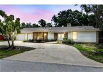 Charming one-story home with white siding, a spacious driveway, and lush landscaping at dusk at 10265 130Th St, Largo, FL 33774